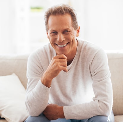 A mature man smiling while sitting on the sofa