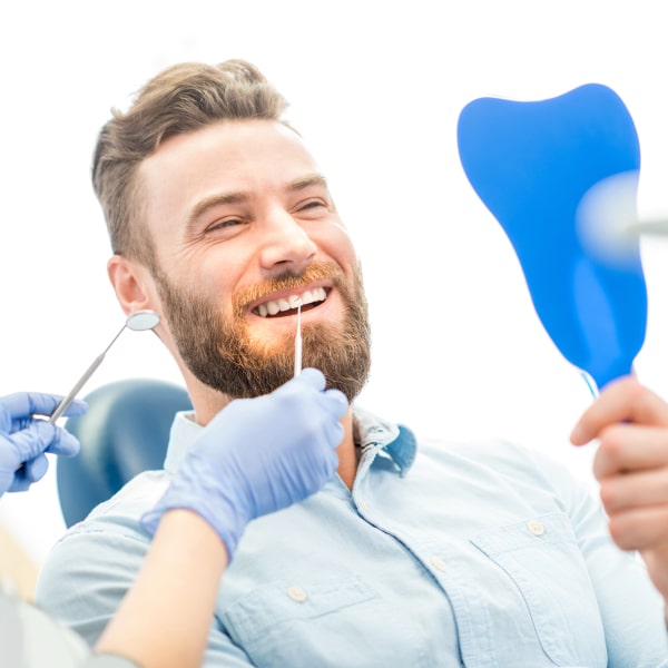 Man looking happy and smiling while sitting in dentistry chair